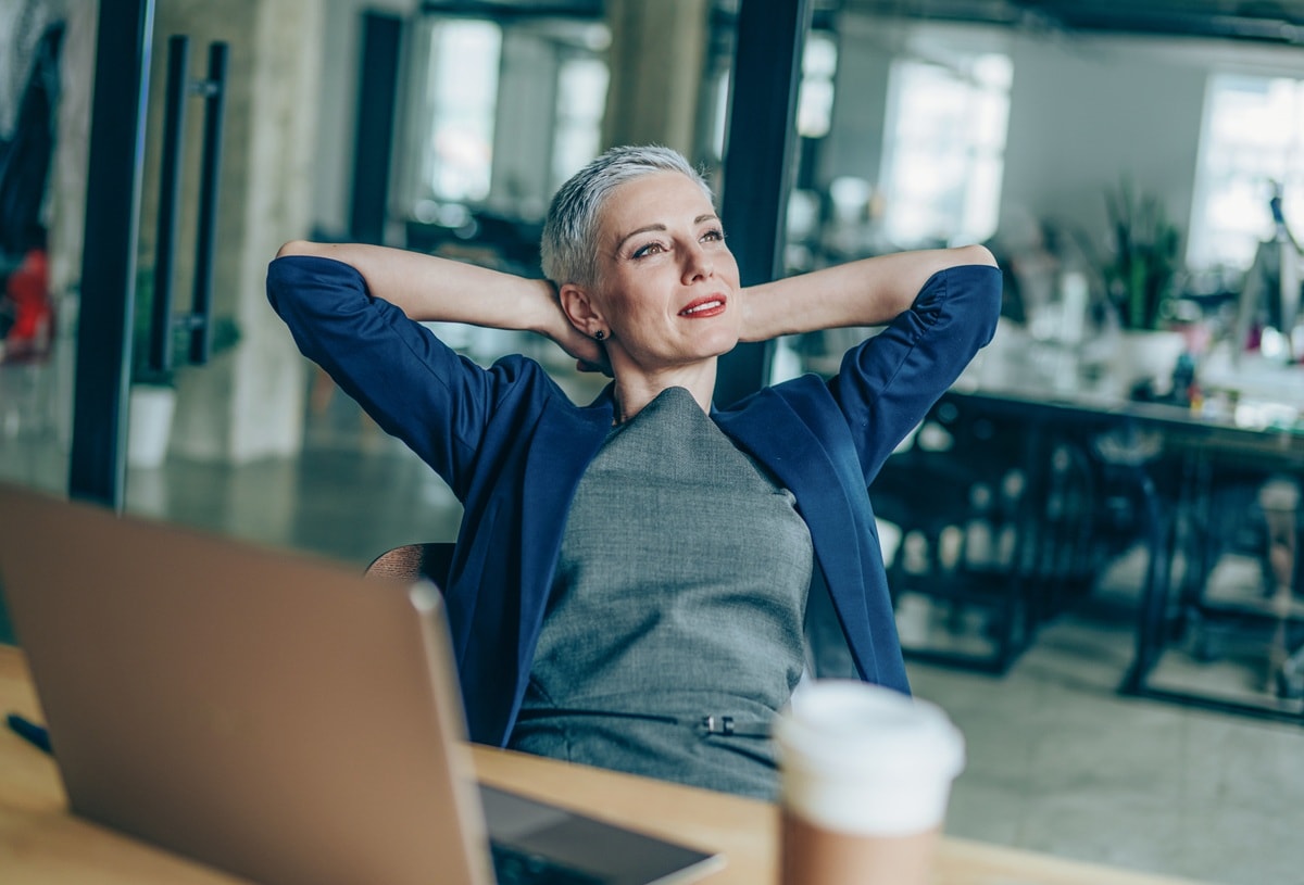 Lady sitting a desk relaxing with arms behind her head
