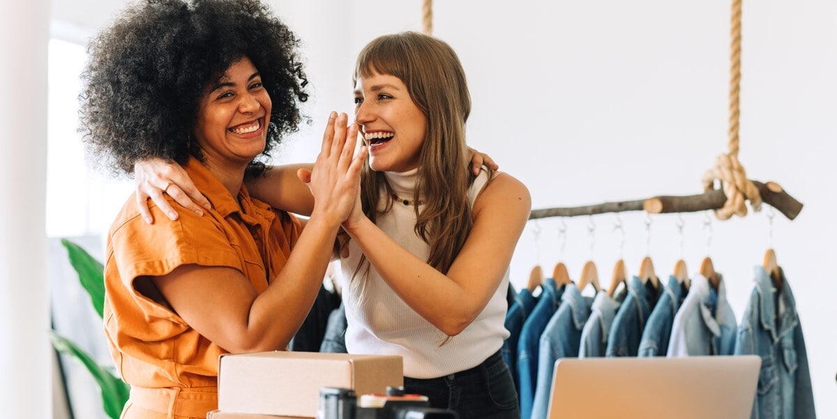 two women high fiving and smiling in a retail store setting