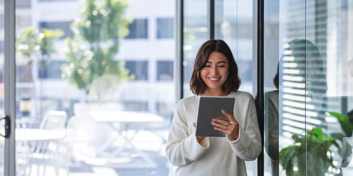 woman standing outside of building, looking at tablet