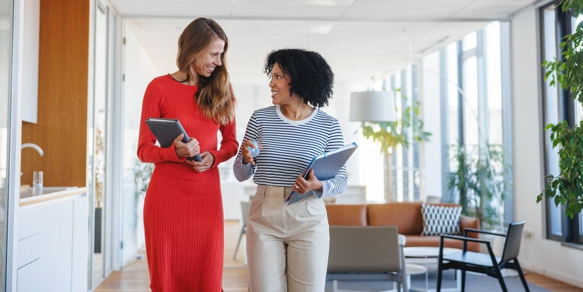 two professional women in office walking down hallway